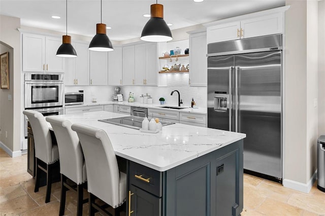 kitchen with white cabinets, stainless steel appliances, sink, and decorative light fixtures