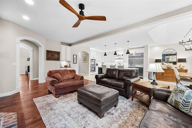 living room featuring beam ceiling, hardwood / wood-style flooring, and ceiling fan with notable chandelier