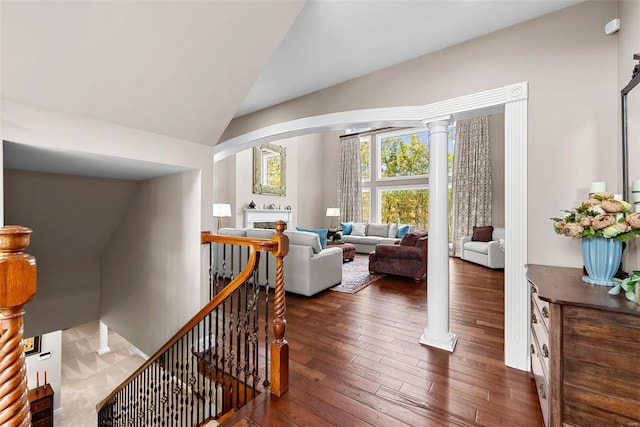 interior space with ornate columns, hardwood / wood-style flooring, and lofted ceiling