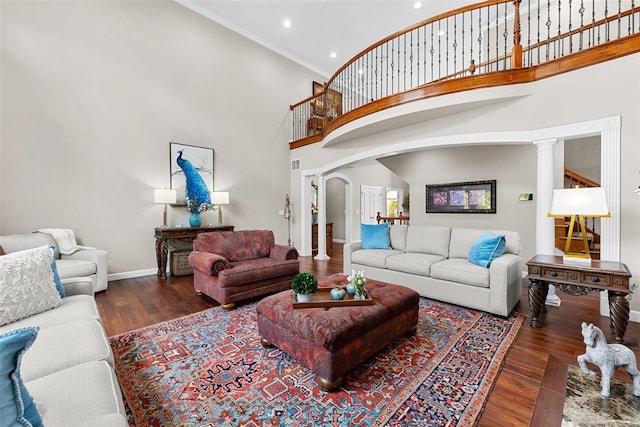 living room with ornate columns, crown molding, dark wood-type flooring, and a high ceiling