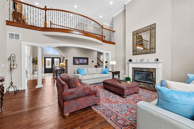 living room featuring decorative columns, french doors, a towering ceiling, and dark hardwood / wood-style flooring