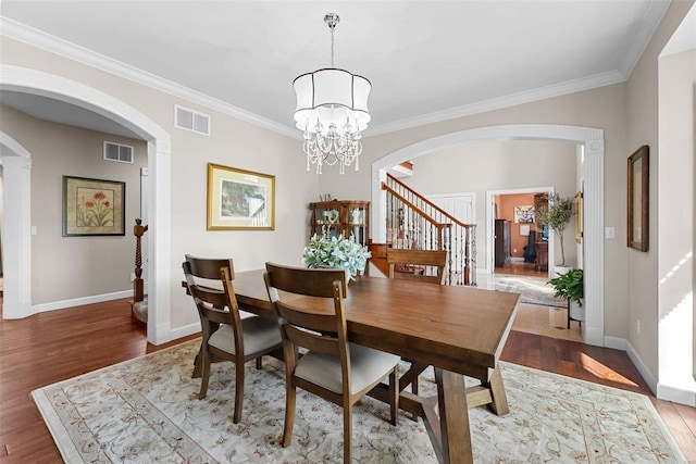 dining room with hardwood / wood-style flooring, ornamental molding, and an inviting chandelier