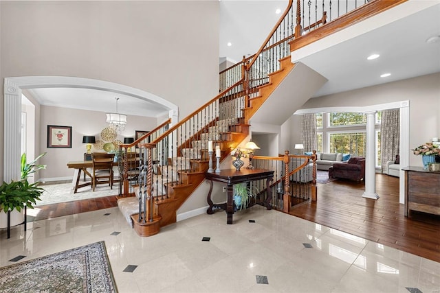 entryway with light hardwood / wood-style floors, ornamental molding, a high ceiling, and a chandelier