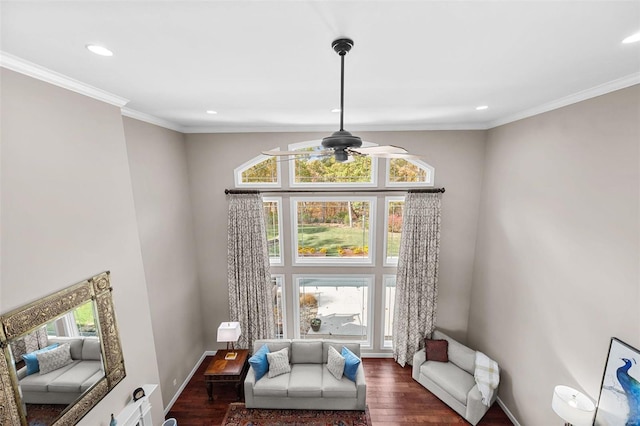 living area featuring dark wood-type flooring, crown molding, a wealth of natural light, and ceiling fan