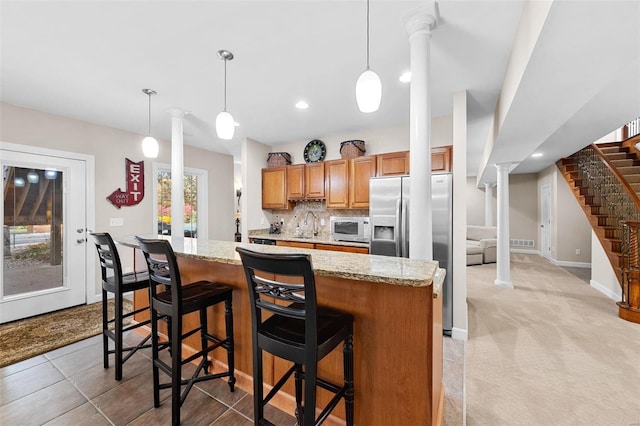 kitchen with pendant lighting, light stone counters, a breakfast bar, light colored carpet, and stainless steel refrigerator with ice dispenser