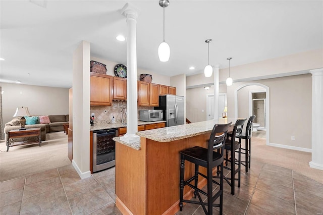 kitchen with light stone counters, appliances with stainless steel finishes, light carpet, and beverage cooler