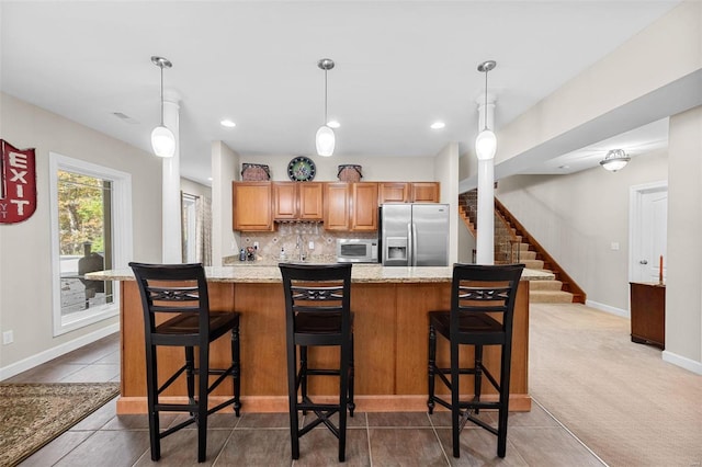 kitchen featuring pendant lighting, a kitchen breakfast bar, stainless steel appliances, and carpet flooring