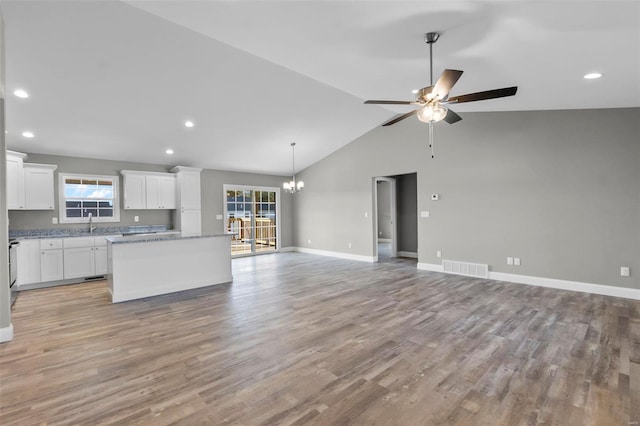 kitchen featuring a center island, light stone counters, white cabinets, ceiling fan with notable chandelier, and light wood-type flooring