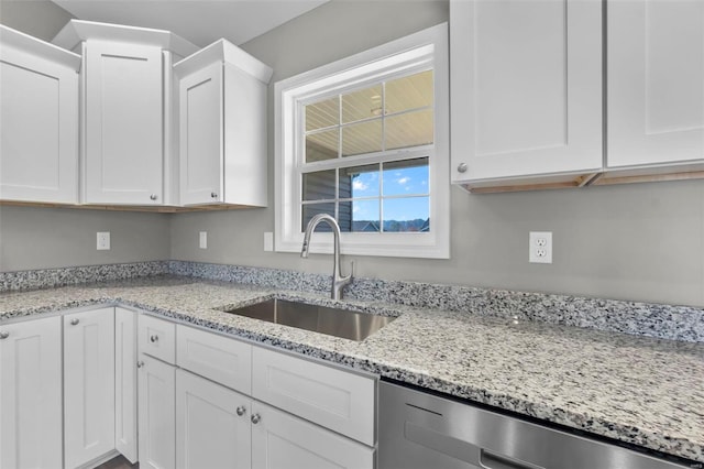 kitchen with white cabinets, light stone counters, dishwasher, and sink