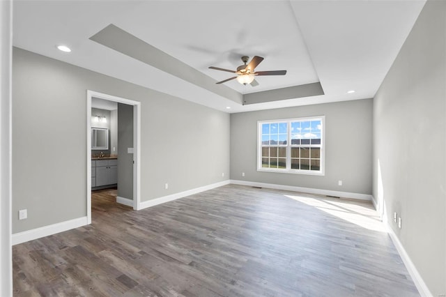 spare room with hardwood / wood-style flooring, ceiling fan, and a tray ceiling