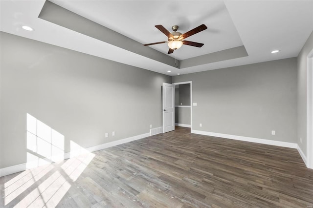 unfurnished room with wood-type flooring, a raised ceiling, and ceiling fan