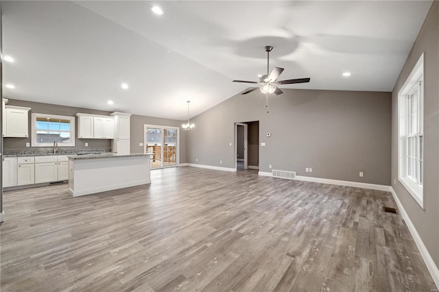 unfurnished living room featuring lofted ceiling, sink, ceiling fan with notable chandelier, and light wood-type flooring