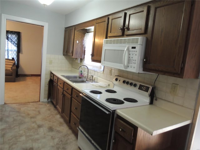 kitchen with dark brown cabinets, white appliances, and sink