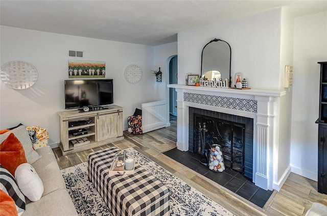 living room featuring a tile fireplace and dark hardwood / wood-style flooring