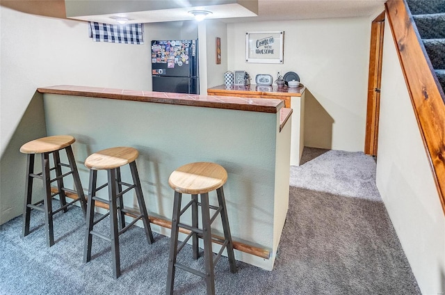 bar featuring black refrigerator, tile countertops, and dark colored carpet