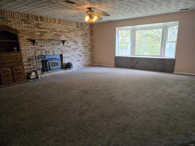 unfurnished living room featuring carpet, ceiling fan, a wood stove, and a textured ceiling