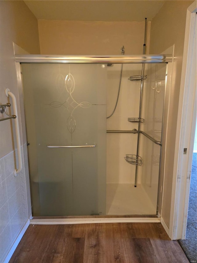 bathroom with hardwood / wood-style floors and a shower with shower door