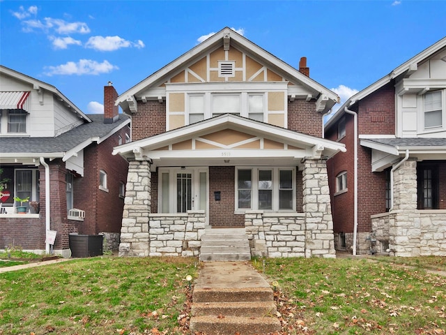 tudor house featuring central AC unit, a porch, and a front yard