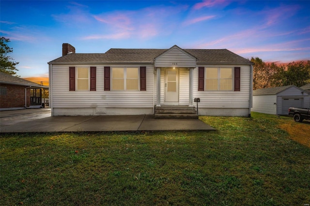 view of front of property featuring an outbuilding, a garage, and a lawn