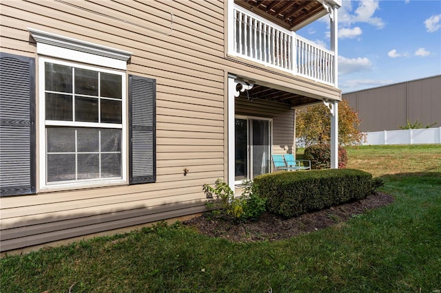 view of side of home featuring a lawn and a balcony