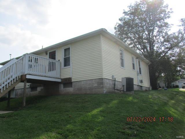 view of side of home with a yard, central AC, and a wooden deck