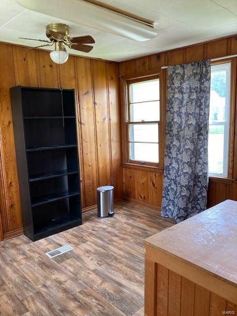 unfurnished bedroom with ceiling fan, wood-type flooring, and wooden walls