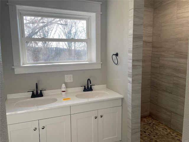 bathroom with a tile shower, vanity, and a wealth of natural light