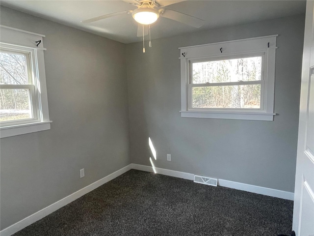 unfurnished room with a wealth of natural light, ceiling fan, and dark carpet