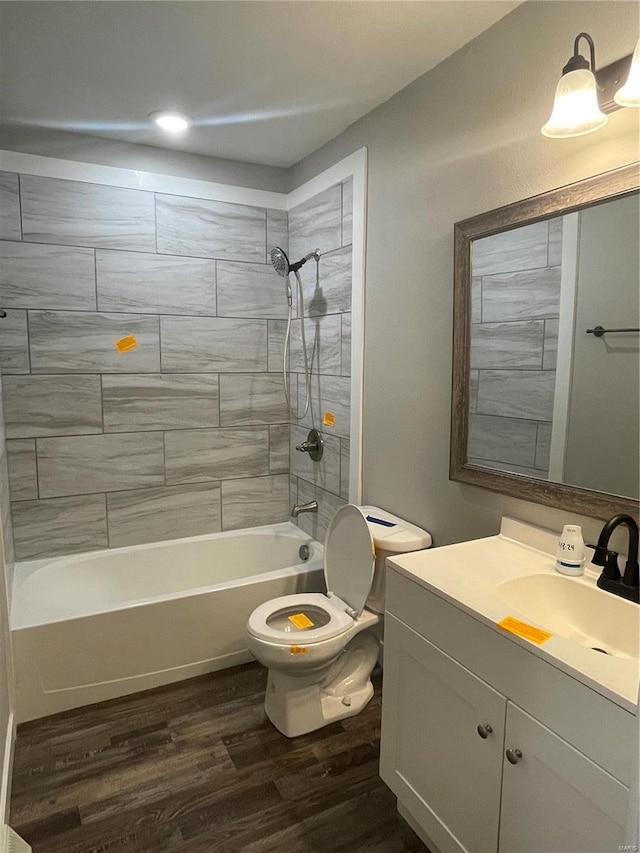 full bathroom with hardwood / wood-style floors, tiled shower / bath combo, toilet, and vanity