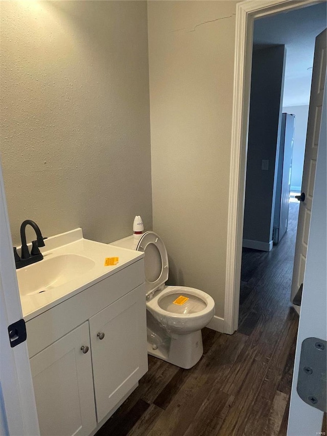 bathroom featuring vanity, hardwood / wood-style flooring, and toilet