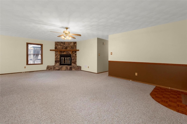 unfurnished living room with ceiling fan, a stone fireplace, carpet flooring, and a textured ceiling