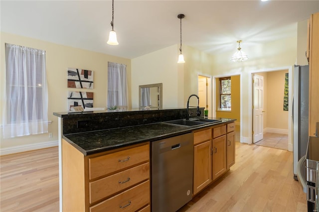 kitchen featuring sink, a center island with sink, dark stone counters, pendant lighting, and stainless steel appliances