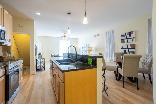 kitchen featuring sink, a breakfast bar area, an island with sink, stainless steel appliances, and light hardwood / wood-style floors