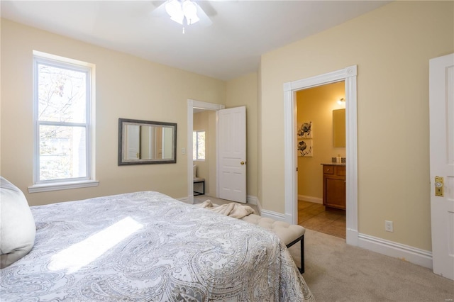 carpeted bedroom featuring multiple windows, connected bathroom, and ceiling fan