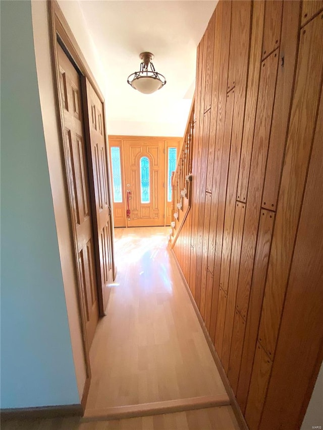 hall with wood-type flooring and wooden walls