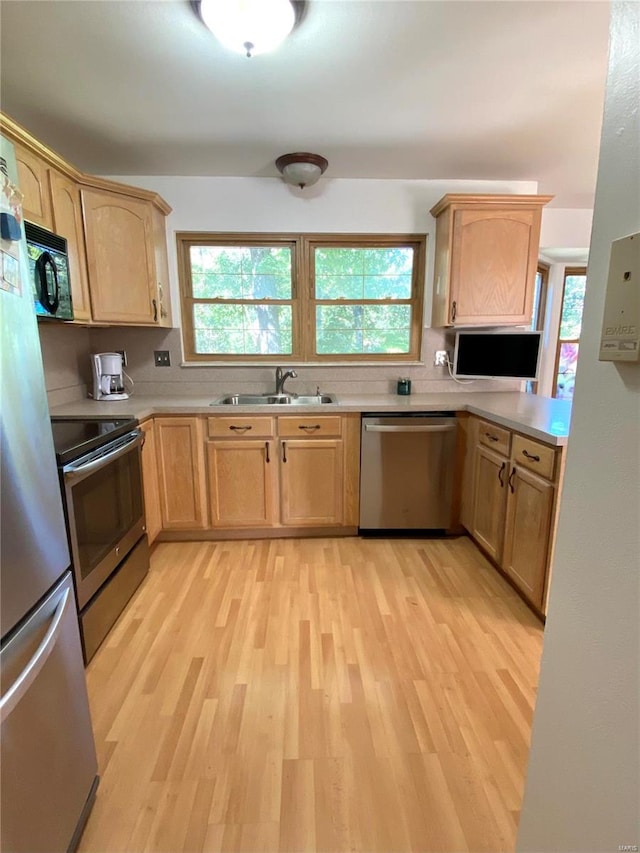 kitchen with light hardwood / wood-style floors, stainless steel appliances, sink, and light brown cabinets