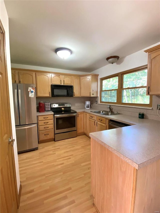 kitchen with light brown cabinetry, sink, stainless steel appliances, and light wood-type flooring