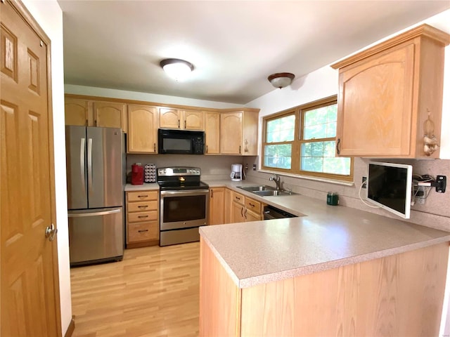 kitchen with light hardwood / wood-style flooring, kitchen peninsula, sink, light brown cabinetry, and appliances with stainless steel finishes