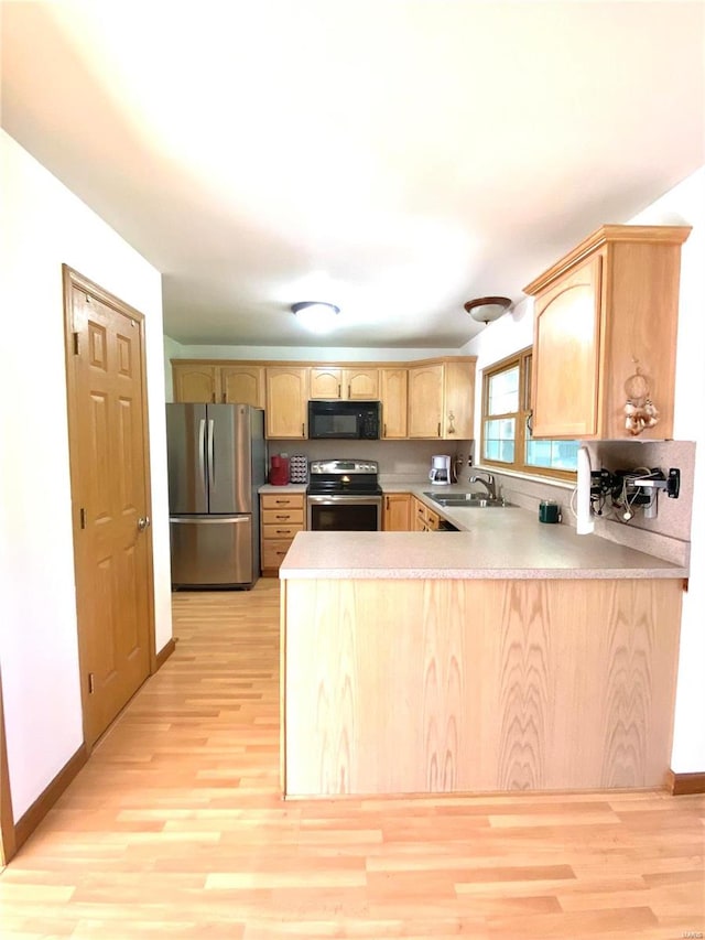 kitchen with appliances with stainless steel finishes, light hardwood / wood-style flooring, and kitchen peninsula