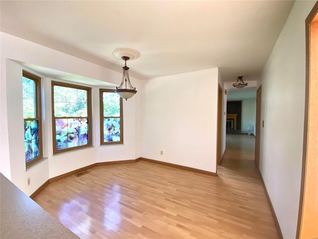 unfurnished room with light hardwood / wood-style flooring and a brick fireplace