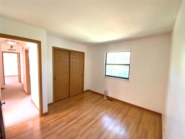 unfurnished bedroom with light hardwood / wood-style floors and a closet