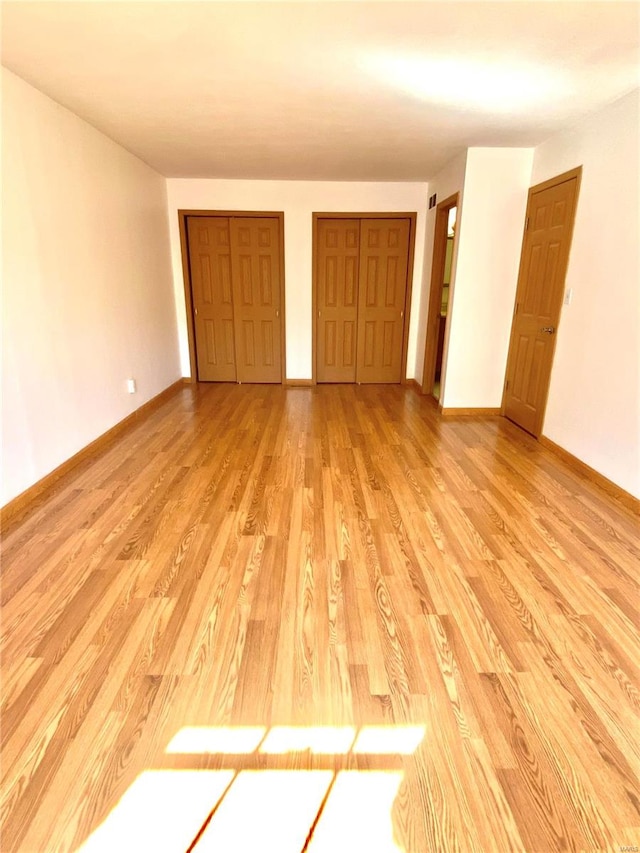 unfurnished bedroom with multiple closets and light hardwood / wood-style flooring