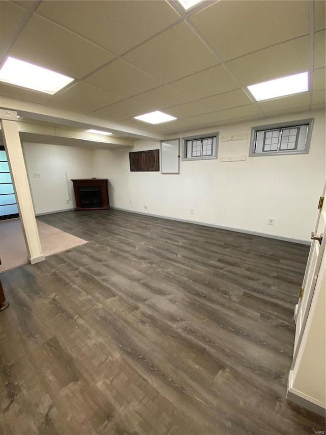 basement featuring a drop ceiling and dark wood-type flooring