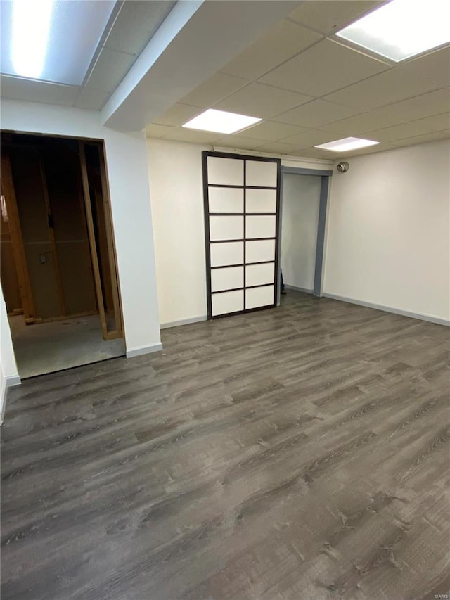 basement with a drop ceiling and dark hardwood / wood-style floors