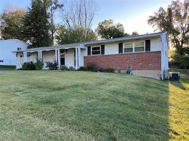 ranch-style home featuring covered porch, a front lawn, and central air condition unit