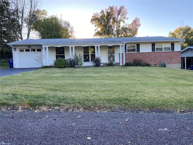 ranch-style house featuring a front lawn, covered porch, and a garage