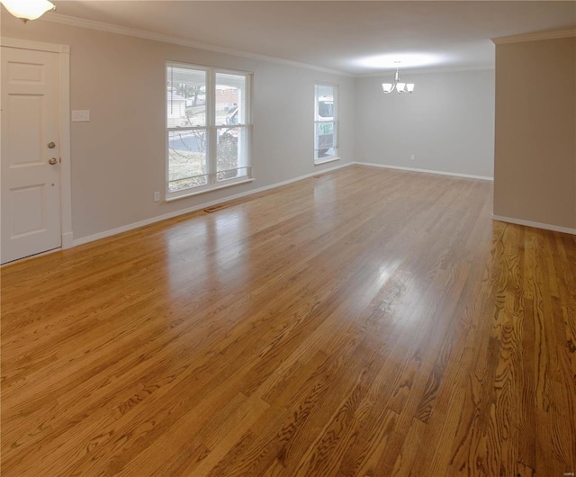 unfurnished room featuring light wood-type flooring, crown molding, and a chandelier