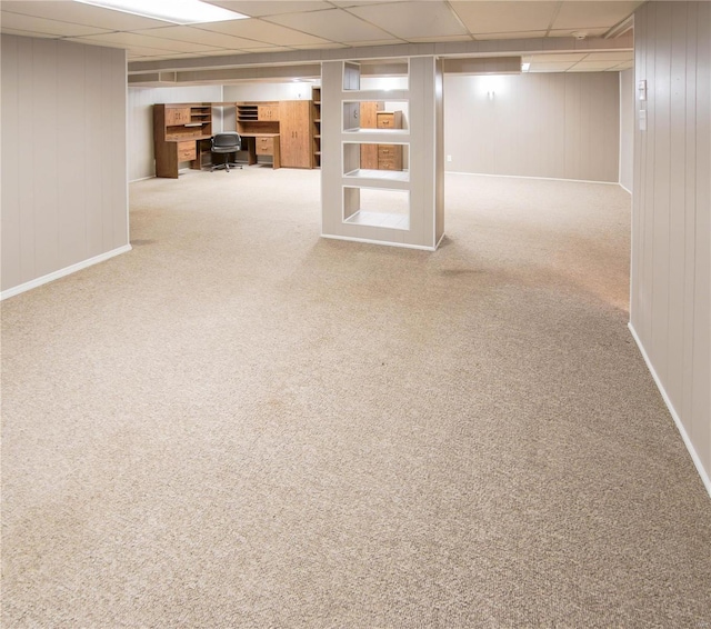 basement featuring carpet, a paneled ceiling, and wood walls