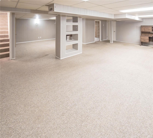 basement with a drop ceiling and light colored carpet