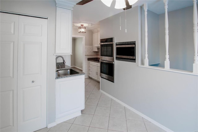 kitchen featuring appliances with stainless steel finishes, tasteful backsplash, sink, light tile patterned floors, and white cabinets